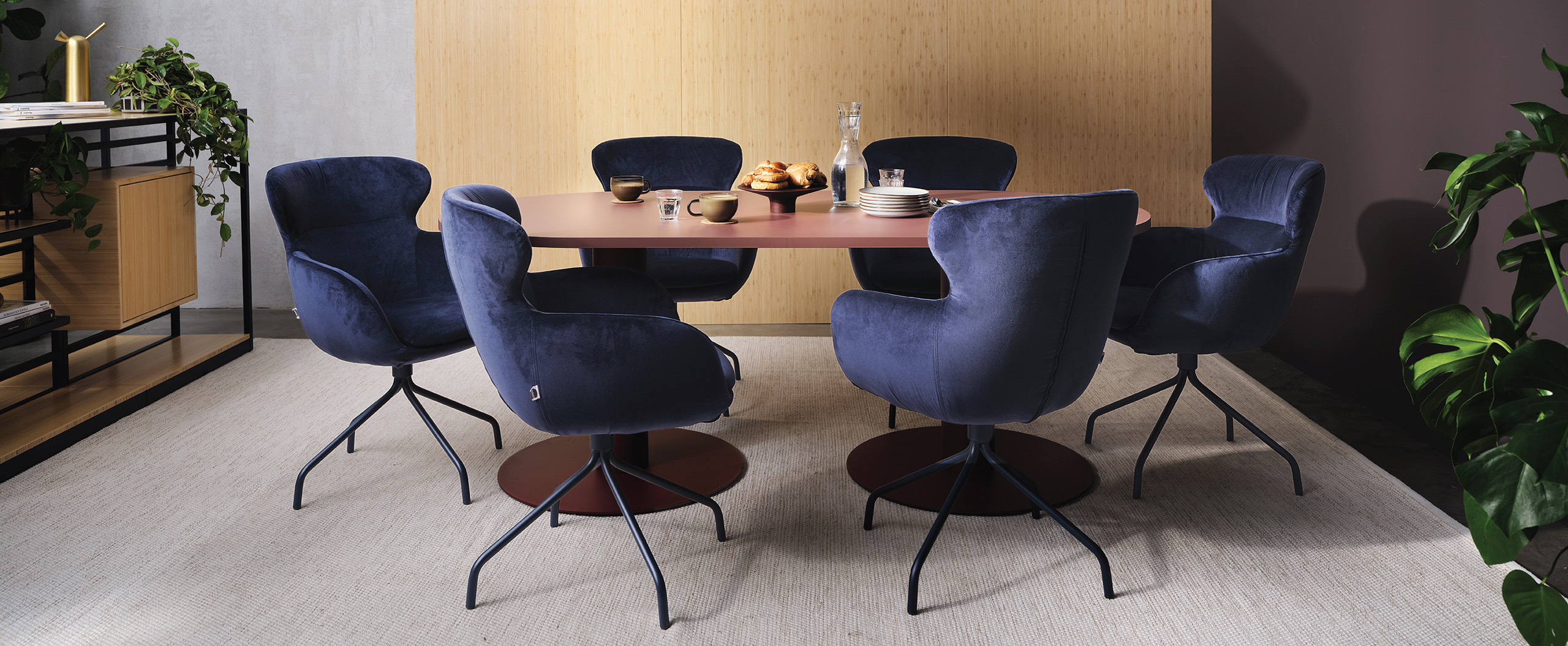 Betto meeting table with a circular pedestal base, shown with four upholstered meeting chairs